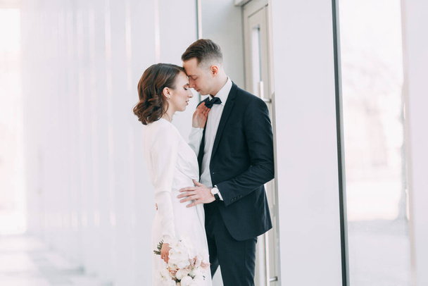 The bride and groom's romantic photo shoot. The newlyweds are happy together. Stylish modern couple in a light interior.  - Φωτογραφία, εικόνα