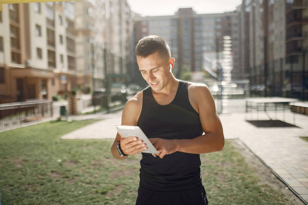 Handsome man standing in a park with a tablet - Foto, Imagen