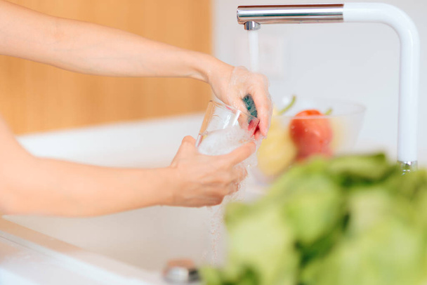 Person Washing a Glass in Kitchen Sink - Fotó, kép