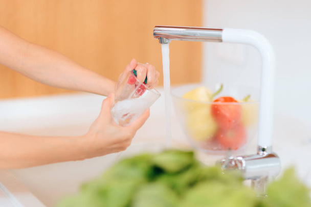 Person Washing a Glass in Kitchen Sink - Фото, изображение