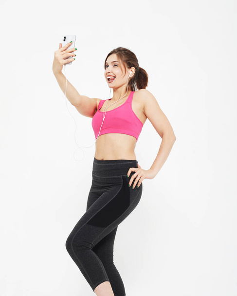 portrait of a smiling fitness woman with smartphone. Selfie time. - Фото, зображення