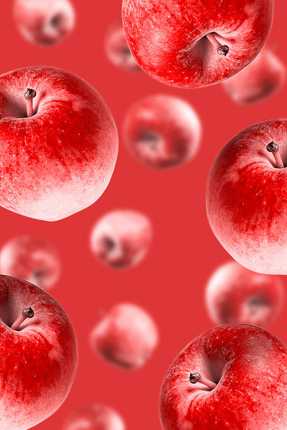 Duże dojrzałe czerwone jabłka spadające od góry do dołu na monochromatyczną czerwień. Otwarta kompozycja. Zbliżenie. Rozmyta perspektywa. - Zdjęcie, obraz