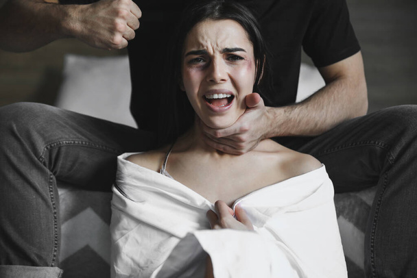 Ο θυμωμένος σύζυγος προσπαθεί να σκοτώσει τη γυναίκα του στο σπίτι. Έννοια της ενδοοικογενειακής βίας - Φωτογραφία, εικόνα