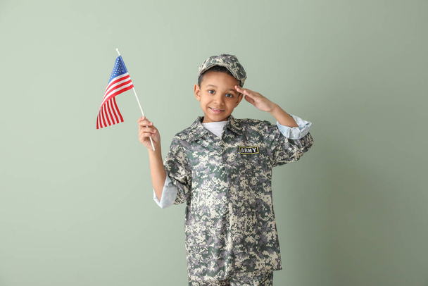 Маленький приветствующий афроамериканский солдат с флагом США на цветном фоне
 - Фото, изображение