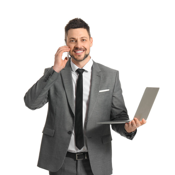 Businessman with laptop talking by phone on white background - Fotoğraf, Görsel