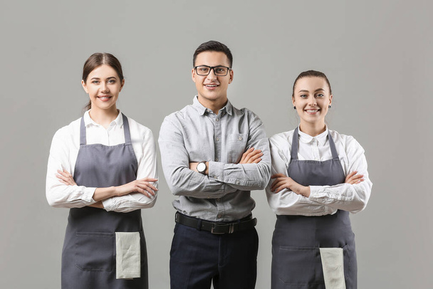 Young waiters with teacher on grey background - Fotó, kép