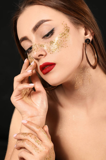 Fashionable young woman with glitters on her body against dark background - Photo, Image