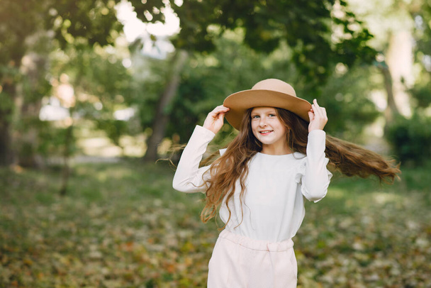 Little girl in a park standing in a park in a brown hat - Фото, зображення