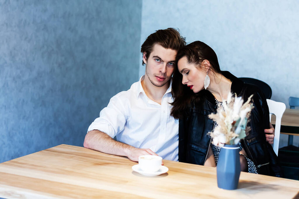 όμορφο ζευγάρι σε ένα καφέ σε ένα τραπέζι πίνει καφέ και μιλάει για κάτι - Φωτογραφία, εικόνα