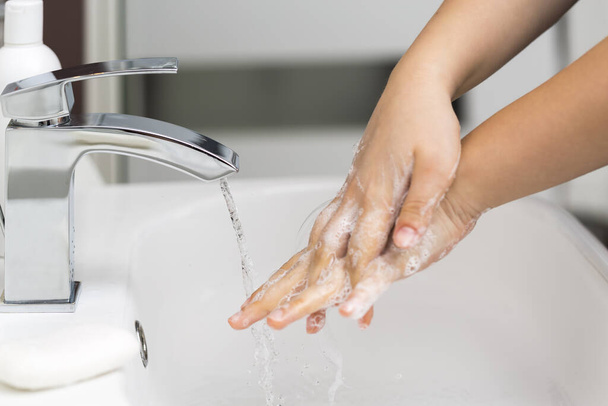 Młoda dziewczyna myje ręce mydłem do zapobiegania koronawirusom, higieny, aby zatrzymać rozprzestrzenianie się koronawirusu. - Zdjęcie, obraz