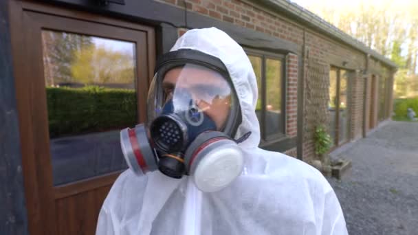 Uomo con maschera respiratoria completa e tuta bianca hazmat che non mostra segni. Pandemia e blocco di coronavirus covid-19 SARS-CoV-2 in tutto il mondo
. - Filmati, video