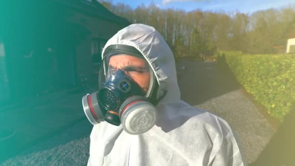 世界中のコロナウイルスの間に完全なマスクと白いハズマットのカバーと青い手袋を身に着けている男covid-19 SARSのCoV-2パンデミックとロックダウン. - 映像、動画