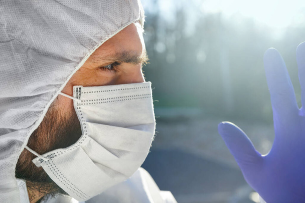 Γιατρός φορώντας αντιιική προστατευτική χειρουργική μάσκα προσώπου και φόρμες κατά τη διάρκεια της πανδημίας του Coronavirus σε όλο τον κόσμο κρίση και κλείδωμα σε Ευρώπη, ΗΠΑ και Κίνα. Επικίνδυνος ιός SARS-CoV-2 Επιδημητικός. - Φωτογραφία, εικόνα