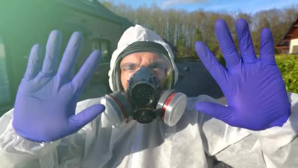 Mężczyzna w pełnej masce respiratora i białej pokrywie ochronnej oraz niebieskich rękawiczkach podczas pandemii i blokady koronawirusa na całym świecie.. - Materiał filmowy, wideo