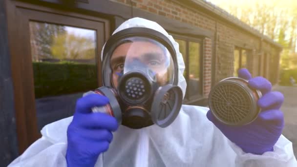 Mężczyzna w pełnej masce respiratora i białym okryciu ochronnym podczas światowej pandemii i zamknięcia koronawirusu covid-19 SARS-CoV-2. - Materiał filmowy, wideo
