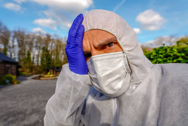 Dokter draagt antivirale beschermende chirurgische gezichtsmasker en overall tijdens Coronavirus pandemie wereldwijde crisis en vergrendeling in Europa, de VS en China. Gevaarlijke SARS-CoV-2 virus Epidemic. - Foto, afbeelding