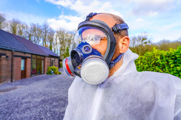 Man met een groot gasmasker tegen Coronavirus Covid-19 besmetting. Afsluiting voor SARS-CoV2 virus pandemie. Post apocalyps specialist ademhaling in anti-virus en stralingsgas masker. Doemsdagkleding - Foto, afbeelding