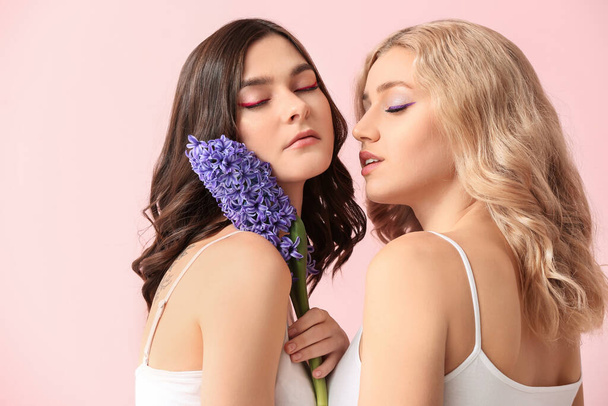 Schöne junge Frauen mit Hyazinthenblüten auf farbigem Hintergrund - Foto, Bild