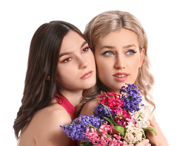 Beyaz arka planda sümbül çiçekleri olan güzel genç kadınlar. - Fotoğraf, Görsel