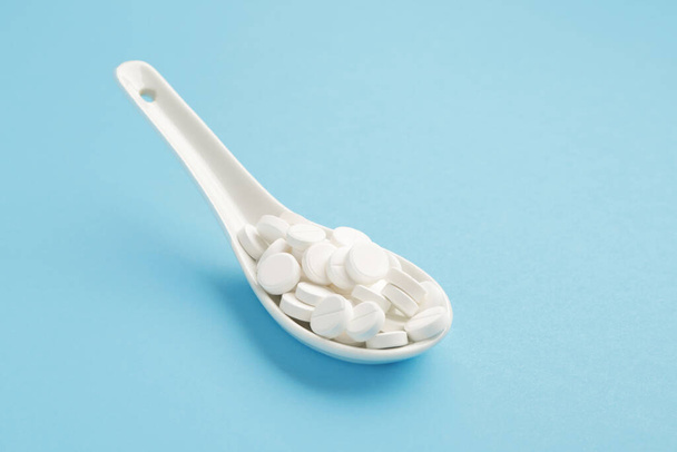 Spoon with pills on color background - Фото, зображення