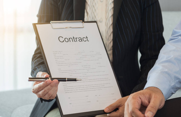 Zakelijke vrouwen sturen pen en contract document naar partner voor ondertekening contract. - Foto, afbeelding