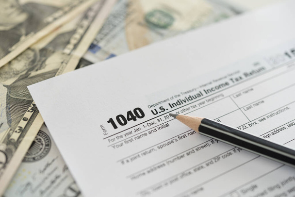アメリカ。個人所得税申告書-ドル紙幣に鉛筆で1040税申告書。税還付の概念、税還付. - 写真・画像