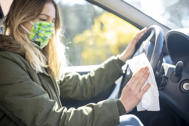 young woman in car disinfecting steering wheel - Photo, Image