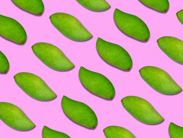 The pattern of the green mangoes is arranged in diagonal lines on a pink background. The background pattern is pink and fresh mangoes. - Photo, image