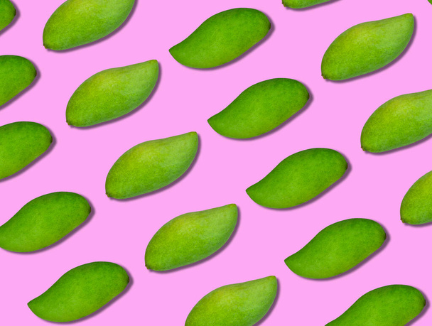 The pattern of the green mangoes is arranged in diagonal lines on a pink background. The background pattern is pink and fresh mangoes. - Photo, image