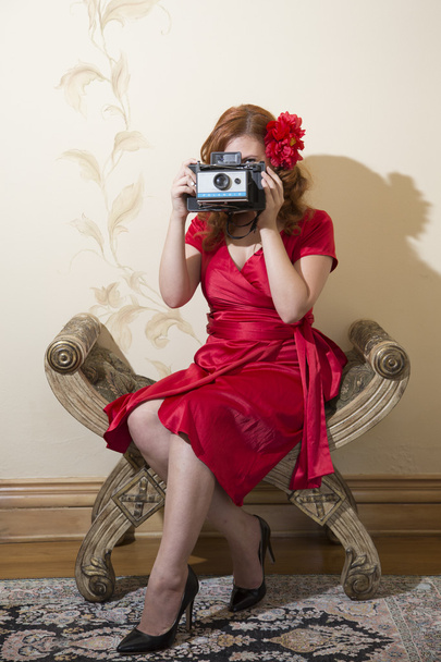 vrouw in een rode jurk een foto neemt - Foto, afbeelding