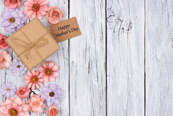 Borde lateral de flores de papel con caja de regalo del día de la madre y etiqueta contra un fondo rústico de madera blanca
 - Foto, imagen