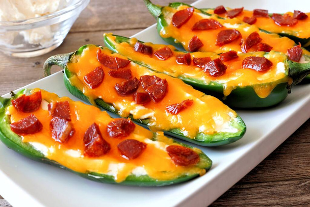 Group of jalapeno poppers with cheese and pepperoni close up on a white serving plate - Photo, Image