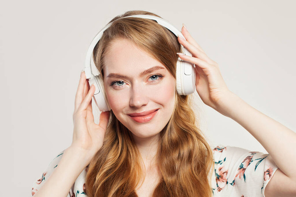 Lovely woman with headphones. Redhead model girl listening music, close up portrait - Photo, image