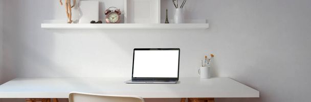 Captura recortada de espacio de trabajo mínimo con computadora portátil de pantalla en blanco y espacio de copia en la mesa blanca con decoraciones en el estante blanco
  - Foto, imagen