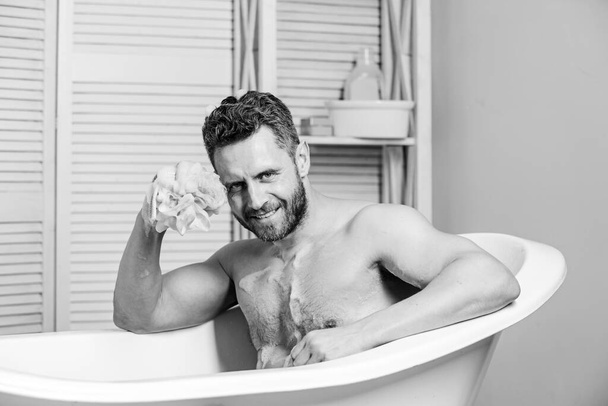 macho man washing in bath. desire and temptation. hygiene and health. Morning shower. man wash muscular body with foam sponge. personal care. Sexy man in bathroom. spa and beauty concept - Фото, зображення