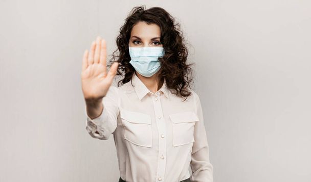 Masked woman makes stopping hand gesture. Influencer Girl blogger in medical mask talks about covid-19, coronavirus. Girl in medical mask stops 2019-nCov - Foto, immagini