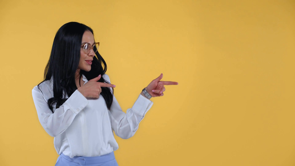 Beautiful businesswoman smiling and pointing with fingers isolated on yellow - Imágenes, Vídeo
