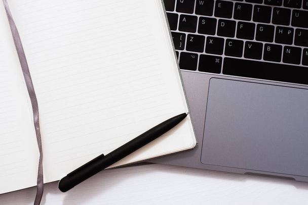 Minimální pracovní prostor. Prázdný notebook s černým perem leží na klávesnici notebooku. - Fotografie, Obrázek