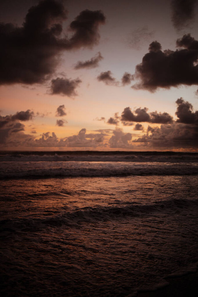 Κόκκινο ηλιοβασίλεμα πάνω από τη θάλασσα. Ο ήλιος αγγίζει τον ορίζοντα. Κόκκινος ουρανός κίτρινος ήλιος και καταπληκτική θάλασσα. Καλοκαιρινή ηλιοθεραπεία. Σύννεφα Spindrift κοσμούν τον ήλιο. Φανταστικό ηλιοβασίλεμα της φύσης - Φωτογραφία, εικόνα