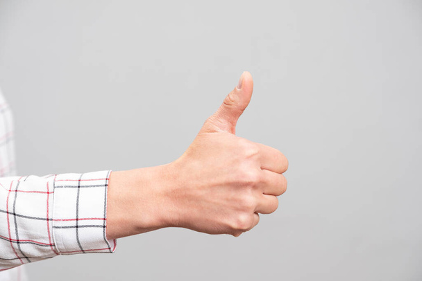 Female hand showing a thumb up sign on a neutral background - Φωτογραφία, εικόνα