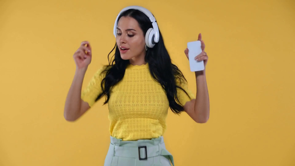 Nainen kuulokkeet tilalla älypuhelin ja tanssia eristetty keltainen
 - Materiaali, video