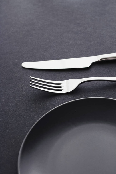 Κενά πιάτα και ασημικά σε μαύρο φόντο, premium επιτραπέζια σκεύη για δείπνο διακοπών, μινιμαλιστικό σχεδιασμό και διατροφή - Φωτογραφία, εικόνα