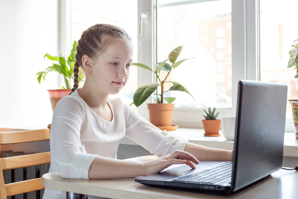 Schoolgirl studying at home using laptop. Home school, online education, home education, quarantine concept - Image - Foto, imagen