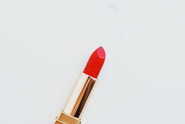Luxury lipstick in a golden tube on white marble background, make-up and cosmetics - Фото, изображение