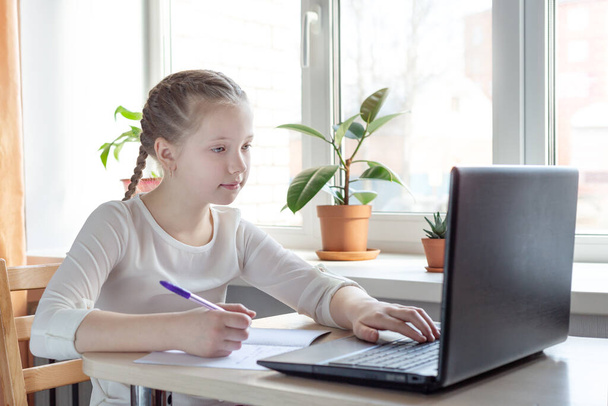 Schoolgirl studying at home using laptop. Home school, online education, home education, quarantine concept - Image - Фото, изображение