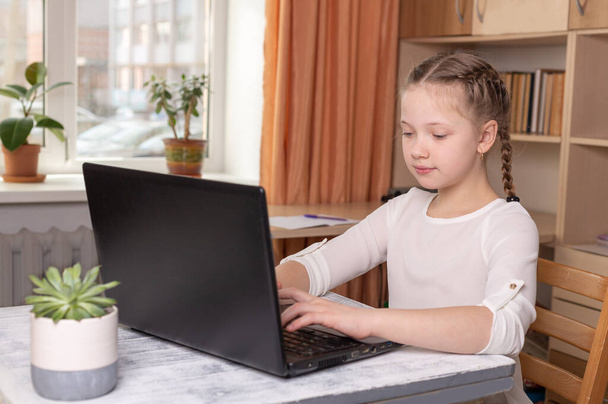 Serious schoolgirl working on a laptop. Distance learning online education, home school, home education, quarantine concept - Image - Фото, зображення