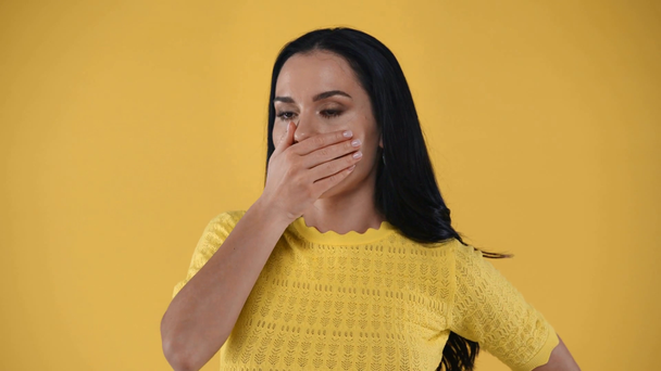 Μπερδεμένη κοπέλα που δείχνει με τα δάχτυλα και μιλάει στην κάμερα απομονωμένη στο κίτρινο - Πλάνα, βίντεο