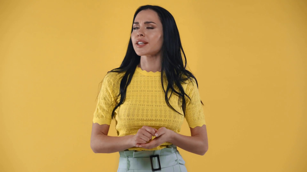 Beautiful girl talking and smiling at camera isolated on yellow - Filmati, video