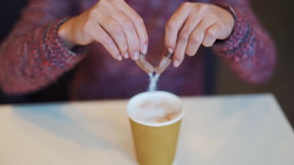 Woman adding sugar to her coffee in a fast food restaurant. Unhealthy eating and drinks concept - Filmati, video