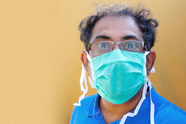 Ritratto di un uomo asiatico del sud che indossa una maschera medica su sfondo giallo
. - Foto, immagini